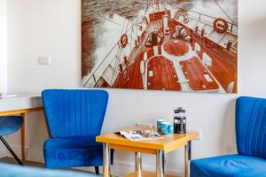 a room with two chairs and a table and a picture of a ship at Colonels Rest - Luxury Beachside Townhouse with Sea Views in Sandown, Sleeps 10 in Sandown