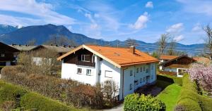 a house with an orange roof with mountains in the background at Bodenschneidsuiten Luxburg in Tegernsee