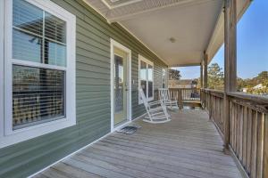 a porch of a house with two chairs on it at All Summer Long by Oak Island Accommodations in Oak Island