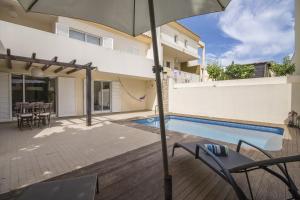 a house with a swimming pool and an umbrella at Casa Oliveira by Algarve Holidays in Loulé