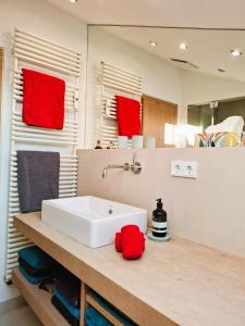 a bathroom with a white sink and red towels at Bodenschneidsuiten Luxburg in Tegernsee +10 photos