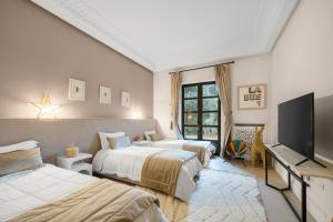 a bedroom with two beds and a flat screen tv at Villa Socar - Heated pool - Padel - Marrakech in Najem