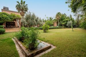 a garden with a pond in front of a house at Villa Socar - Heated pool - Padel - Marrakech in Najem
