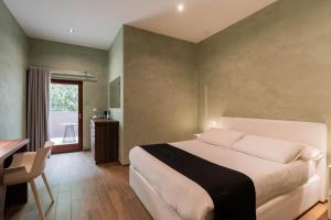 a bedroom with a large bed and a table and a window at Quaint Boutique Hotel Sannat in Sannat