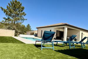 two blue chairs sitting in the grass next to a house at Villa Dyane in Salavas