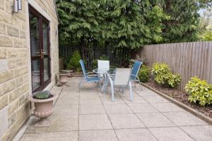 a patio with chairs and a table and a fence at Large 2-Bedroom Bungalow near Airedale Hospital, Keighley, Convenient Location with Parking in Steeton