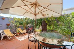 a patio with a glass table and an umbrella at Casa Vacanze Bouganvillea in Sabaudia