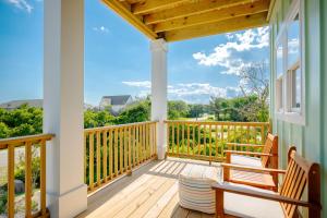 a porch with two chairs and a wooden deck at All Sands On Deck by Oak Island Accommodations in Oak Island