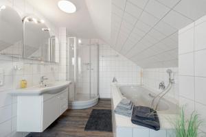 a white bathroom with a tub and a sink at Ferienwohungen Otto und Grete in Hemmoor +37 photos
