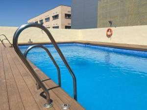 a swimming pool with a metal handrail next to a building at Lux Sevilla Apartment Piscina in Bormujos