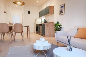 a living room with a couch and a table at Les Suites du Parc - Elégance et lumière face au Parc Simone Veil appartement 2 chambres à 2 minutes des halles in Sète