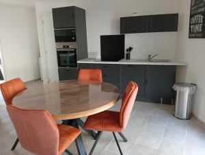 a kitchen with a wooden table and orange chairs at Le logis de la liane in Boulogne-sur-Mer