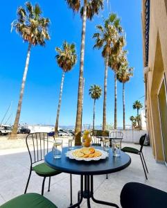 a table with a plate of food on a patio with palm trees at Latchi Marina in Lachi
