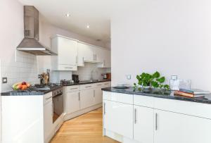 a kitchen with white cabinets and black counter tops at Fabulous Apartment Central London in London