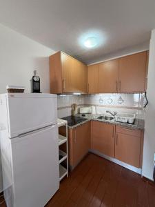 a kitchen with a white refrigerator and wooden cabinets at Apartamento Oura - Albufeira in Bicas