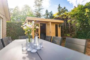 a table with a vase of flowers on it at Luxe wellnesshuis op de Veluwe in Lunteren