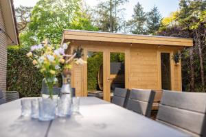 a table with a vase of flowers on top of it at Luxe wellnesshuis op de Veluwe in Lunteren