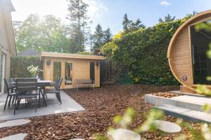 a backyard with a table and chairs and a house at Luxe wellnesshuis op de Veluwe in Lunteren