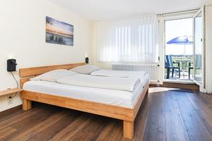 a bedroom with a bed and a large window at Pension Sielmöwe in Neuharlingersiel