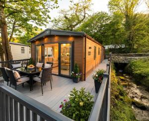 a tiny house with a table and chairs on a deck at Aberdunant Hall Holiday Park, Snowdonia in Porthmadog