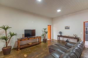 a living room with a leather couch and a flat screen tv at Casa da Matriz in Pirenópolis