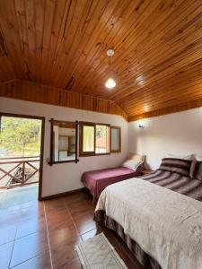a bedroom with two beds and a wooden ceiling at Chales Vale da Nascente in Monte Verde