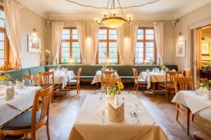 a restaurant with tables and chairs and a green couch at Parkhotel Güldene Berge in Weißenfels