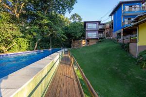 a swimming pool next to a building with a green yard at Siriúba Reserve in Ilhabela