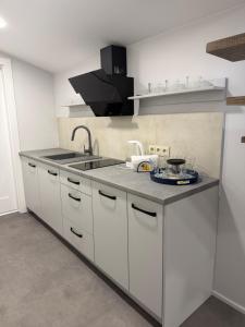 a kitchen with white cabinets and a sink at Apartamentai LUKA in Marijampolė