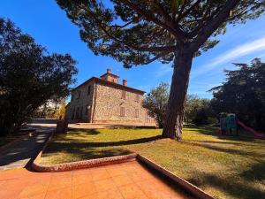 an old brick building with a tree and a playground at Maison Antoinette in San Vincenzo