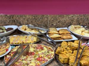 a table with many different types of food on plates at Domus Hotel Trindade - Canaã dos Carajás in Canaã dos Carajás