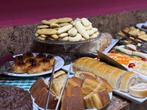 a table filled with different types of bread and pastries at Domus Hotel Trindade - Canaã dos Carajás in Canaã dos Carajás +12 photos