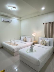 two beds in a room with white walls at Khaosok Embrace Resort in Khao Sok National Park