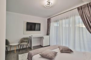 a bedroom with a bed and a desk and a television at Pe Coastă in Cozăneşti