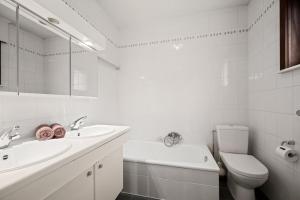 a white bathroom with a sink and a toilet at Bretoenselaan 5 in De Haan