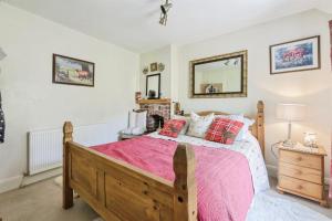 a bedroom with a large bed with a pink bedspread at Coachman's Cottage B & B in Plymouth