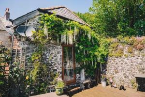 a stone house with plants on the side of it at Coachman's Cottage B & B in Plymouth