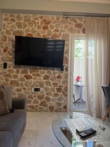 a living room with a tv on a stone wall at Stone house 48 m in Acharnes