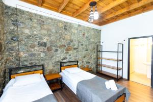 two beds in a room with a stone wall at Mestia HOTEL AMIRANI in Mestia