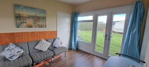 a living room with a couch and a sliding glass door at Beside the Seaside Chalet in Mablethorpe