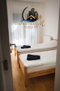 two beds in a room with a sign on the wall at ApartmanMFoca in Foča