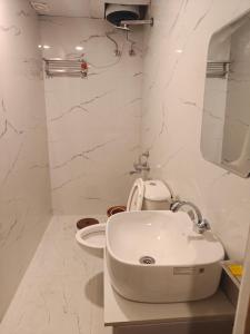 a white bathroom with a sink and a toilet at Blue Breeze in Haridwār
