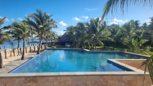 a swimming pool next to a beach with palm trees at Villa Sedeoen in Nembrala