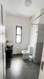 a white bathroom with a toilet and a sink at GL Luxe Suites in Tatu City +16 photos