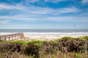 a beach with a wooden boardwalk and the ocean at Beach Therapy by Oak Island Accommodations in Caswell Beach