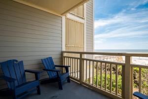 two blue chairs sitting on a porch looking out at the ocean at Beach Therapy by Oak Island Accommodations in Caswell Beach