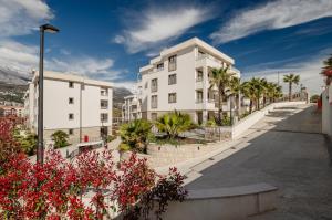 a white building with palm trees and a street at River side apartment B17 in Herceg-Novi