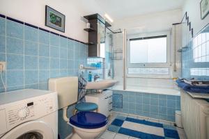 a blue tiled bathroom with a toilet and a sink at Adlerhorst in Wangen +7 photos