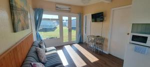 a living room with a couch and a sliding glass door at Beside the Seaside Chalet in Mablethorpe