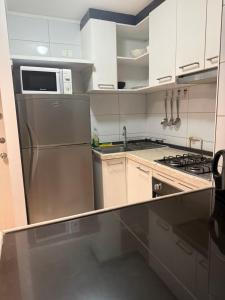 a kitchen with a stainless steel refrigerator and a microwave at 703 Departamento 15 minutos de Aeropuerto Maipu in Santiago